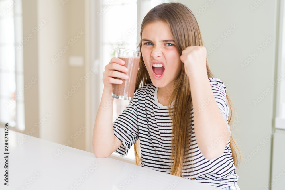 Beautiful young girl kid drinking fresh tasty chocolate milkshake as snack annoyed and frustrated shouting with anger, crazy and yelling with raised hand, anger concept Beautiful young girl kid drinking fresh tasty chocolate milkshake as snack annoyed and frustrated shouting with anger, crazy and yelling with raised hand, anger concept