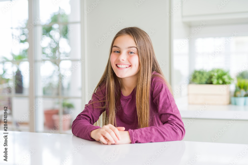 Beautiful young girl kid on white table with a happy and cool smile on face. Lucky person.