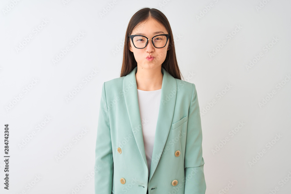 Chinese businesswoman wearing elegant jacket and glasses over isolated white background puffing cheeks with funny face. Mouth inflated with air, crazy expression.