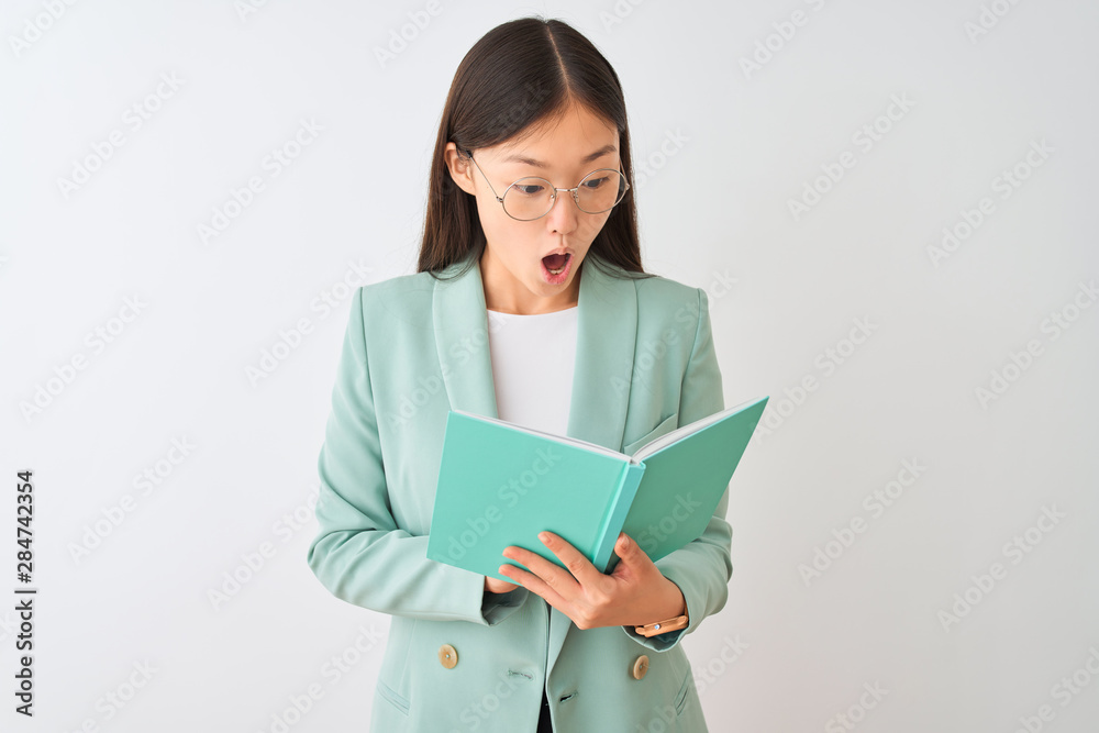Young chinese student woman wearing glasses reading book over isolated white background scared in shock with a surprise face, afraid and excited with fear expression Young chinese student woman wearing glasses reading book over isolated white background scared in shock with a surprise face, afraid and excited with fear expression