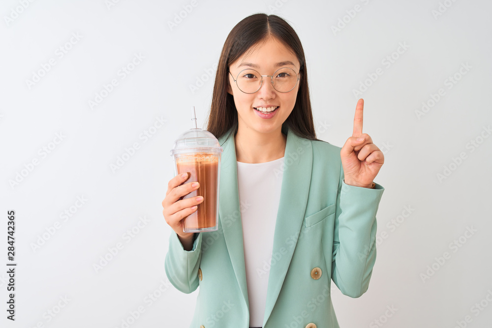 Young chinese woman drinking tomato smoothie over isolated white background surprised with an idea or question pointing finger with happy face, number one Young chinese woman drinking tomato smoothie over isolated white background surprised with an idea or question pointing finger with happy face, number one
