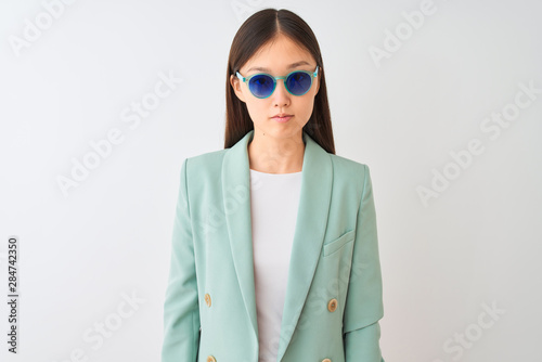 Chinese businesswoman wearing jacket and sunglasses over isolated white background with a confident expression on smart face thinking serious