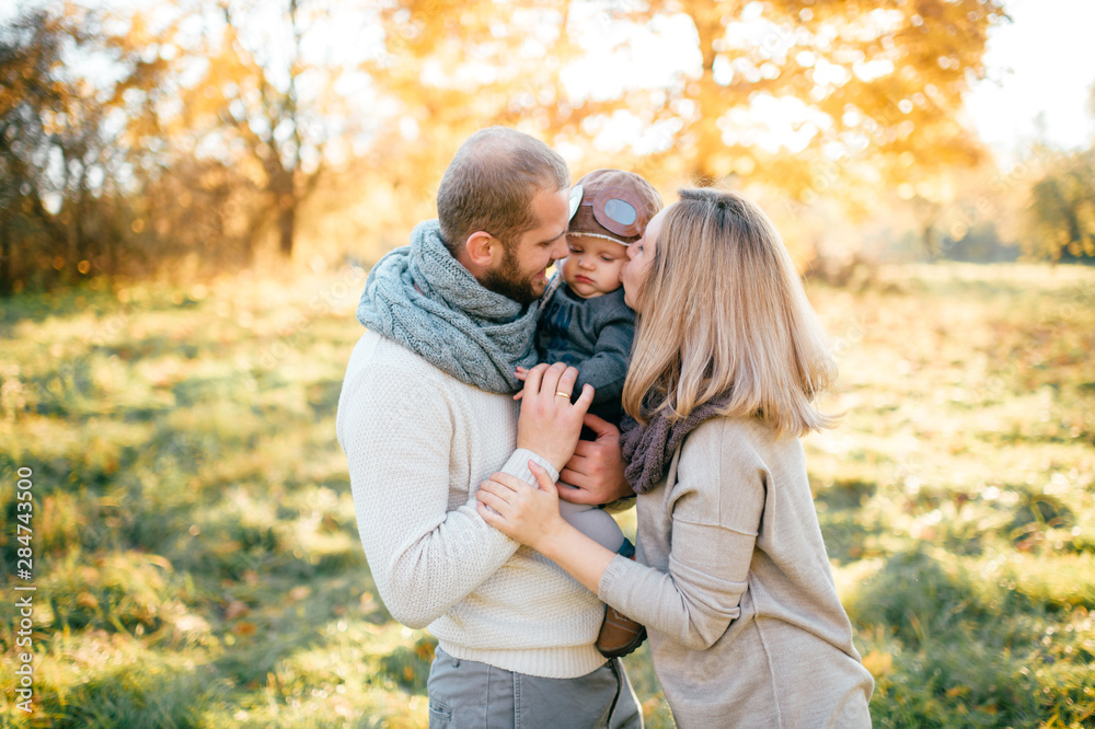 Happy family couple with child in pilot helmet sincere emotions outdoor portrait.