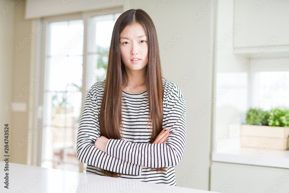 Beautiful Asian woman wearing stripes sweater skeptic and nervous, disapproving expression on face with crossed arms. Negative person. Beautiful Asian woman wearing stripes sweater skeptic and nervous, disapproving expression on face with crossed arms. Negative person.