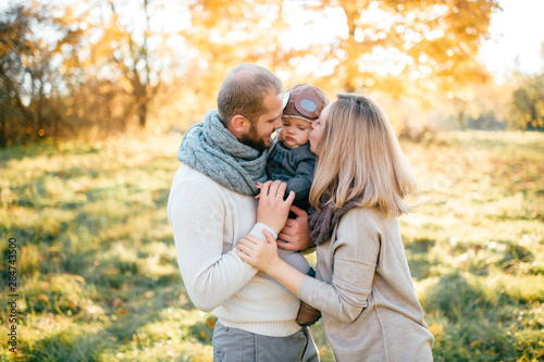 Happy family couple with child in pilot helmet sincere emotions outdoor portrait.