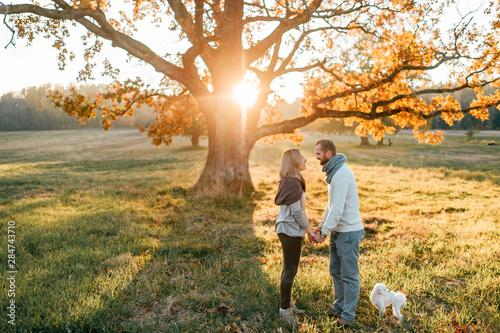 Young loving couple walking and hugging in autumn field at sunset