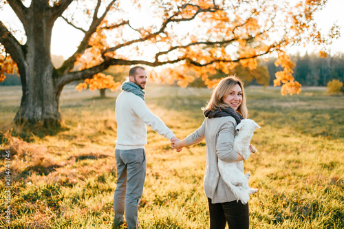 Young loving couple walking and hugging in autumn field at sunset