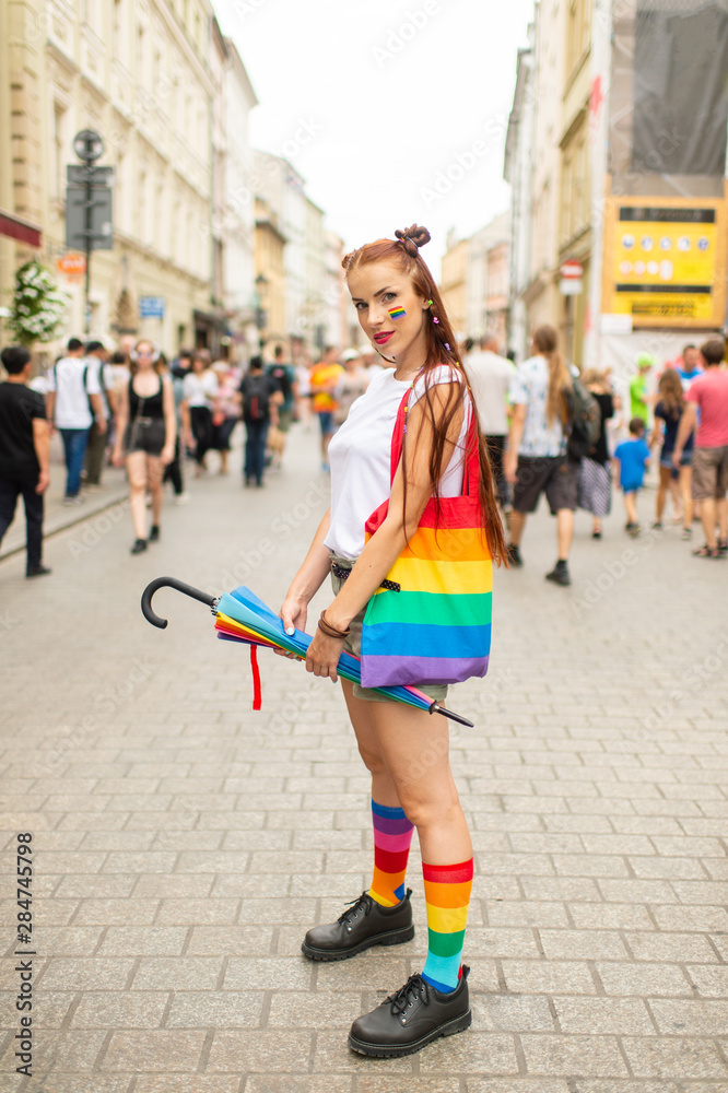 Lifestyle portrait of lesbian with lgbt flag on her face posing on the street