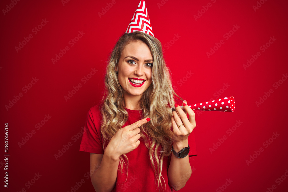 Young beautiful woman on birthday celebration over red isolated background very happy pointing with hand and finger Young beautiful woman on birthday celebration over red isolated background very happy pointing with hand and finger