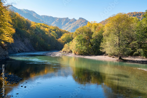 Peaceful autumn landscape with wide mountain river and forest © Yakov