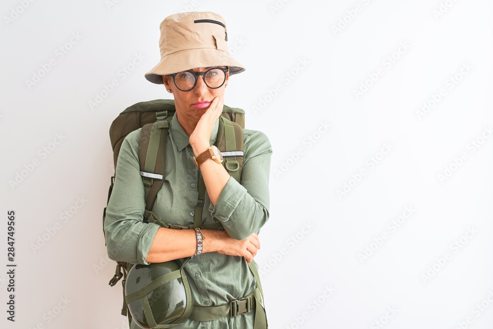 Fototapeta premium Middle age hiker woman wearing backpack canteen hat glasses over isolated white background thinking looking tired and bored with depression problems with crossed arms.