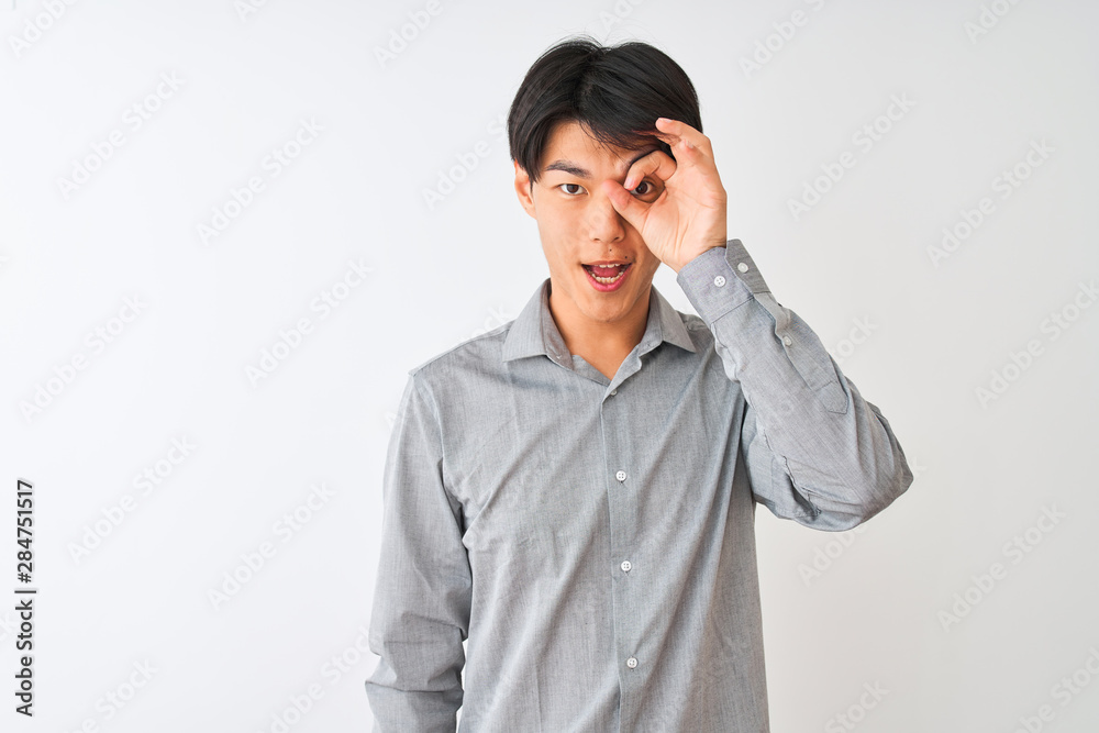 Chinese businessman wearing elegant shirt standing over isolated white background doing ok gesture with hand smiling, eye looking through fingers with happy face. Chinese businessman wearing elegant shirt standing over isolated white background doing ok gesture with hand smiling, eye looking through fingers with happy face.
