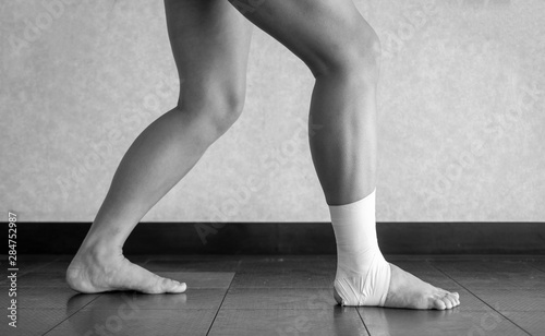 Black and white version of Athlete doing a calf stretch with an ankle tape job 