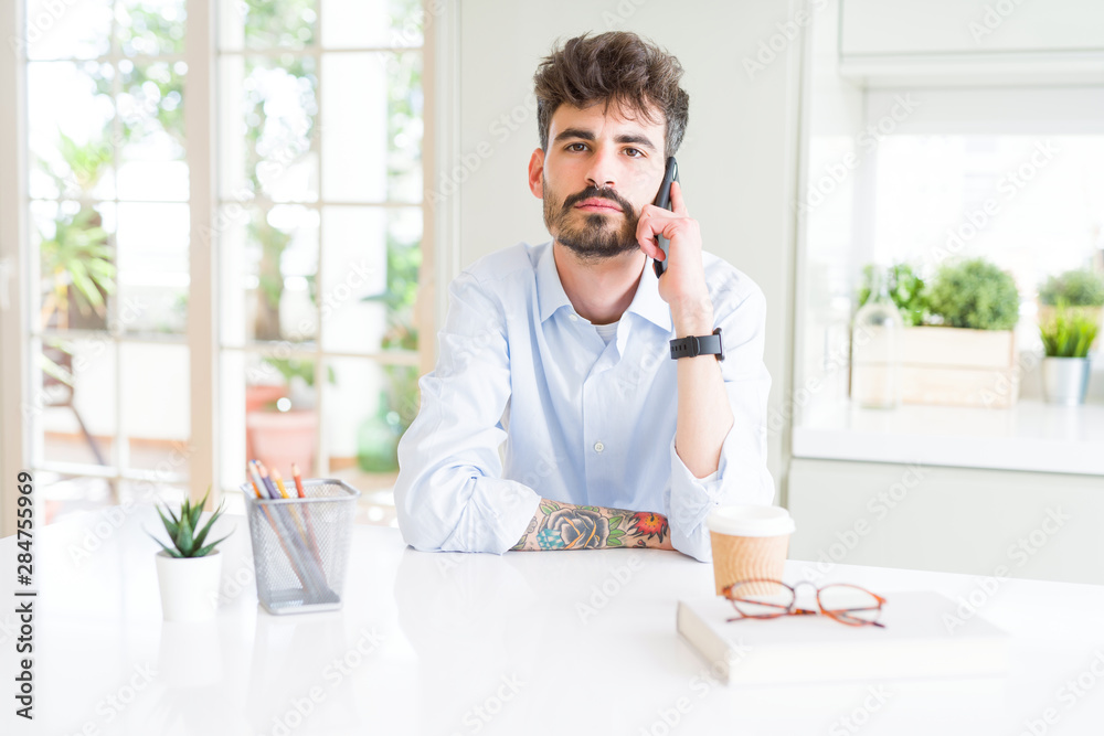 Young business man talking on smartphone with a confident expression on smart face thinking serious