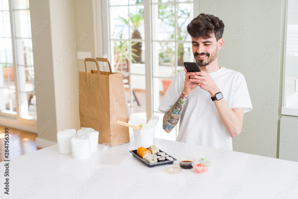Young man taking pictures with smartphone of sushi asian food from take away delivery Young man taking pictures with smartphone of sushi asian food from take away delivery