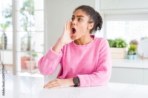 Free Download Beautiful african american woman with afro hair wearing casual pink sweater shouting and screaming loud to side with hand on mouth. Communication concept. - GFXLoad