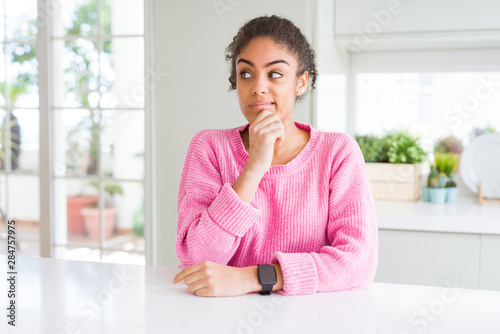 Beautiful african american woman with afro hair wearing casual pink sweater Thinking worried about a question, concerned and nervous with hand on chin