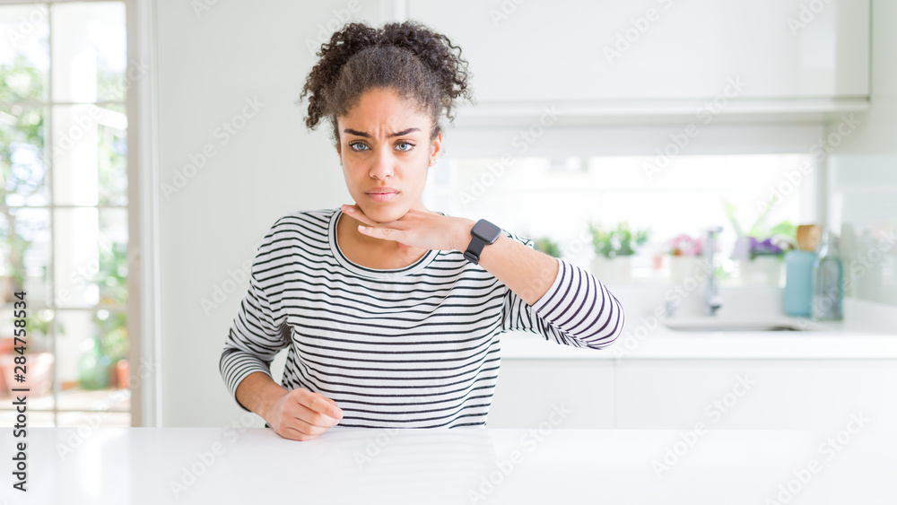 Beautiful african american woman with afro hair wearing casual striped sweater cutting throat with hand as knife, threaten aggression with furious violence Beautiful african american woman with afro hair wearing casual striped sweater cutting throat with hand as knife, threaten aggression with furious violence