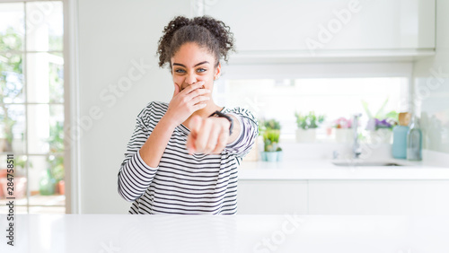 Beautiful african american woman with afro hair wearing casual striped sweater laughing at you  pointing finger to the camera with hand over mouth  shame expression