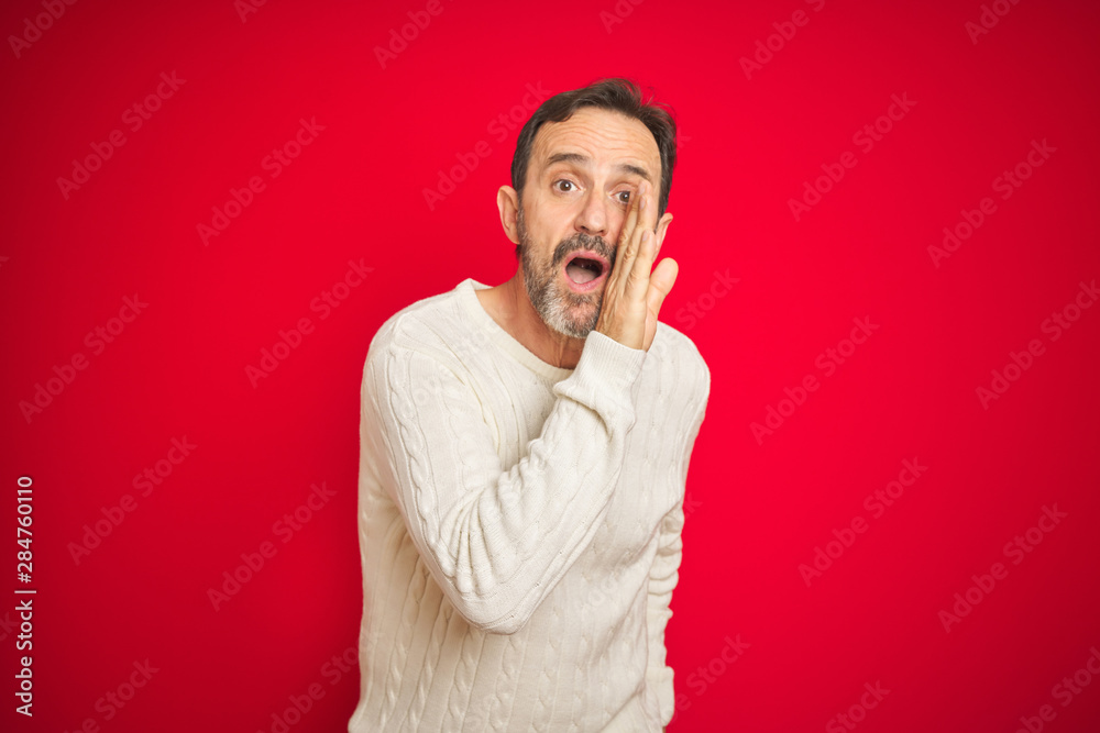 Handsome middle age senior man with grey hair over isolated red background hand on mouth telling secret rumor, whispering malicious talk conversation