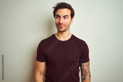 Wallpaper Mural Young handsome man with tattoo wearing purple casual t-shirt over isolated white background smiling looking to the side and staring away thinking. Torontodigital.ca