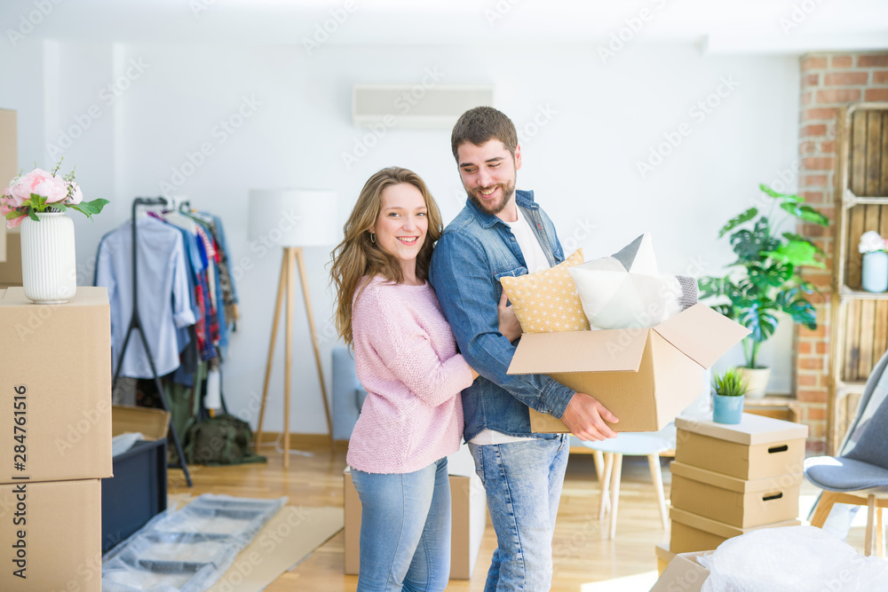 Young beautiful couple very happy together holding cardboard boxes moving to a new home Young beautiful couple very happy together holding cardboard boxes moving to a new home