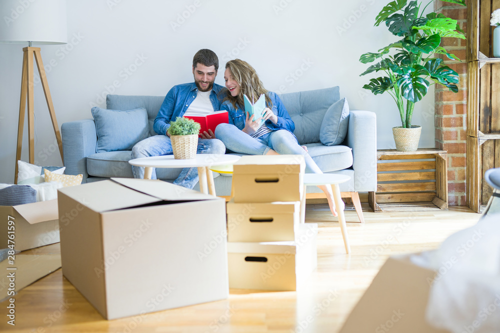 Young couple relaxing on the sofa reading a book, taking a break for moving to new house Young couple relaxing on the sofa reading a book, taking a break for moving to new house
