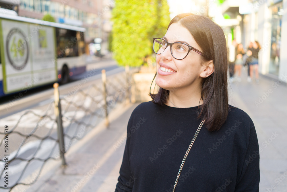 Beautiful young brunette woman smiling excited walking down the city streets, happy and confident expression standing outdoors at the town