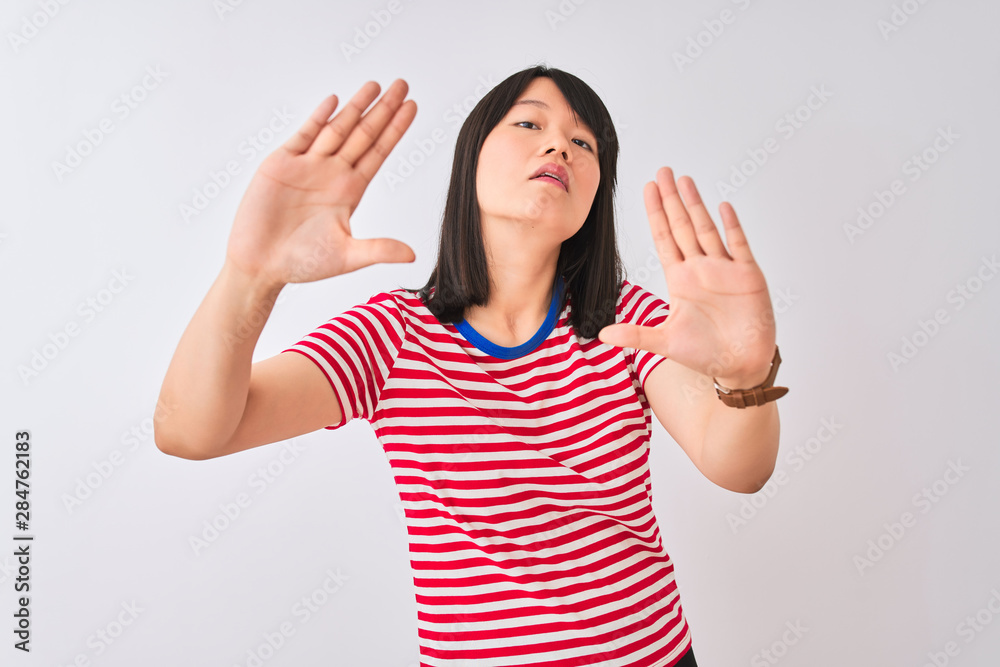 Young beautiful chinese woman wearing red striped t-shirt over isolated white background doing frame using hands palms and fingers, camera perspective Young beautiful chinese woman wearing red striped t-shirt over isolated white background doing frame using hands palms and fingers, camera perspective