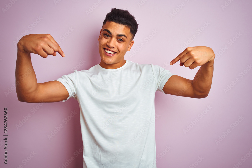 Young brazilian man wearing t-shirt standing over isolated pink background looking confident with smile on face, pointing oneself with fingers proud and happy. Young brazilian man wearing t-shirt standing over isolated pink background looking confident with smile on face, pointing oneself with fingers proud and happy.