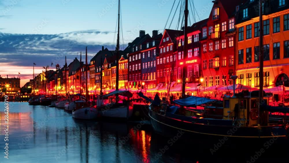 Copenhagen, Denmark. Time-lapse at sunset. View of famous Nyhavn area in the center of Copenhagen, Denmark. Various boats moored with historical buildings and cloudy sunset bright sky, panning video