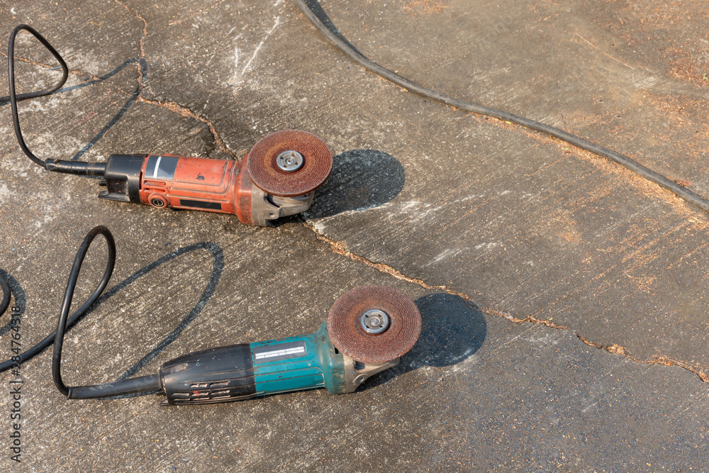 Angle grinder isolated on cement floor background. Construction concept.