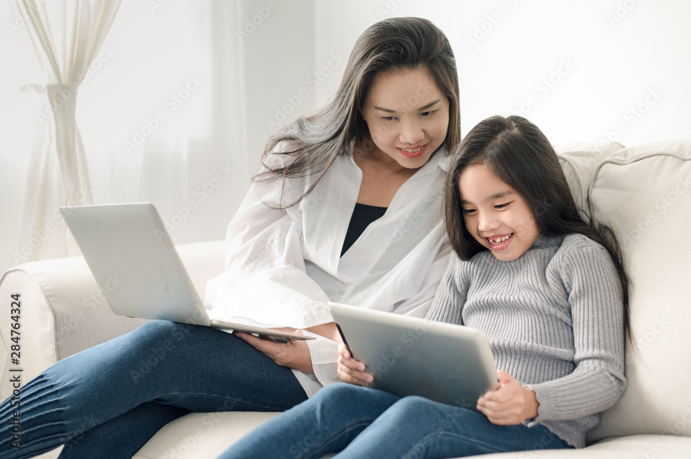 happy mother and daughter with laptop and tablet pc happy mother and daughter with laptop and tablet pc