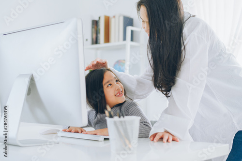 happy Little girl looking at computer with her mother