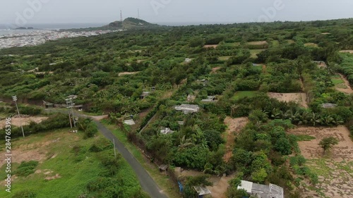 At one exotic island in Vietnam, tilt up shot with a village of traditional Vietnamese houses and patches of lush plants running into the far horizon. Tilt up shot. photo