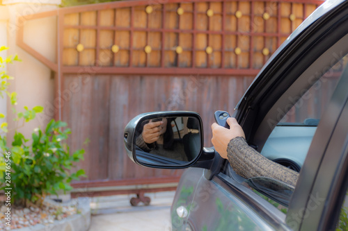 Woman in car, hand opening the automatic gate by using remote control. The auto door and security system concept.