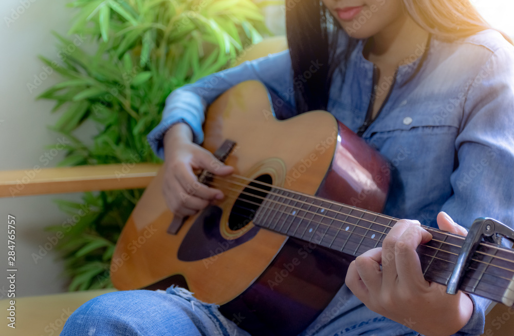 Fototapeta premium Young asian teen smiling girl enjoy playing guitar in free time at home. Hobby lifestyle and Leisure time concept. 