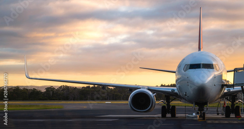 Sunset view of airplane on airport runway under dramatic sky in Hobart,Tasmania, Australia. Aviation technology and world travel concept.