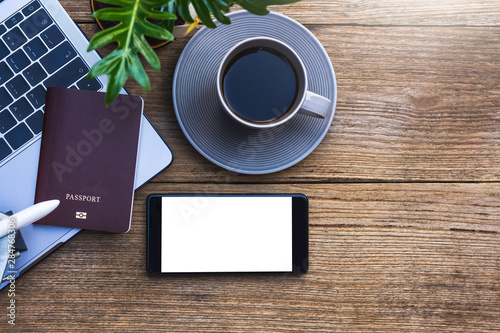 Mobile smartphone,passport, laptop ,airplane and cup of coffee mock up design template isolated on wooden table background. Business and technology concept. Clipping path and copy space.Top view