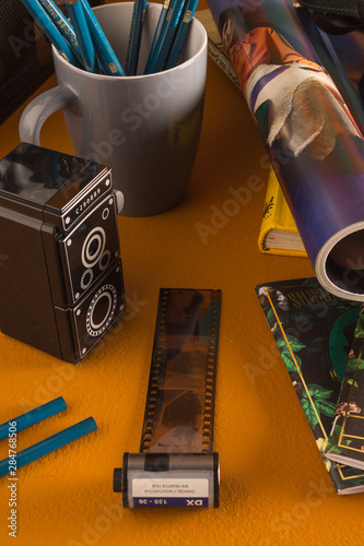 Película de rollo de cámara con portalápices gris con cuadros azules y sacapuntas con forma de cámara sobre fondo amarillo photo