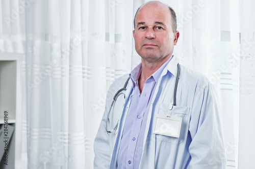 Portrait of sad serious doctor in white labcoat with empty badge looking at camera