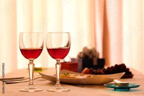 Dinner Time with a couple, Decorate dining table by gift boxes, red wine glass, food, beverage and fruits for the festival to celebrate. He prepares a gift with girl friend in the night party. Cheers! © Photo Sesaon