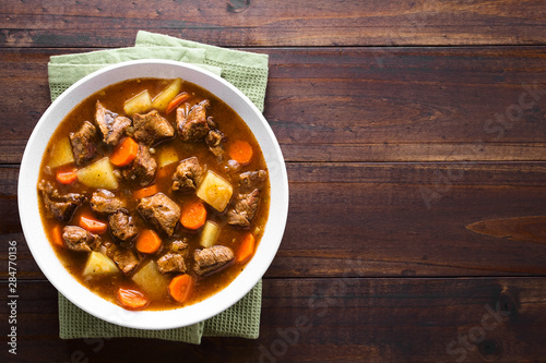Fresh homemade beef stew with carrot and potatoes served in bowl, photographed overhead with copy space on the side photo