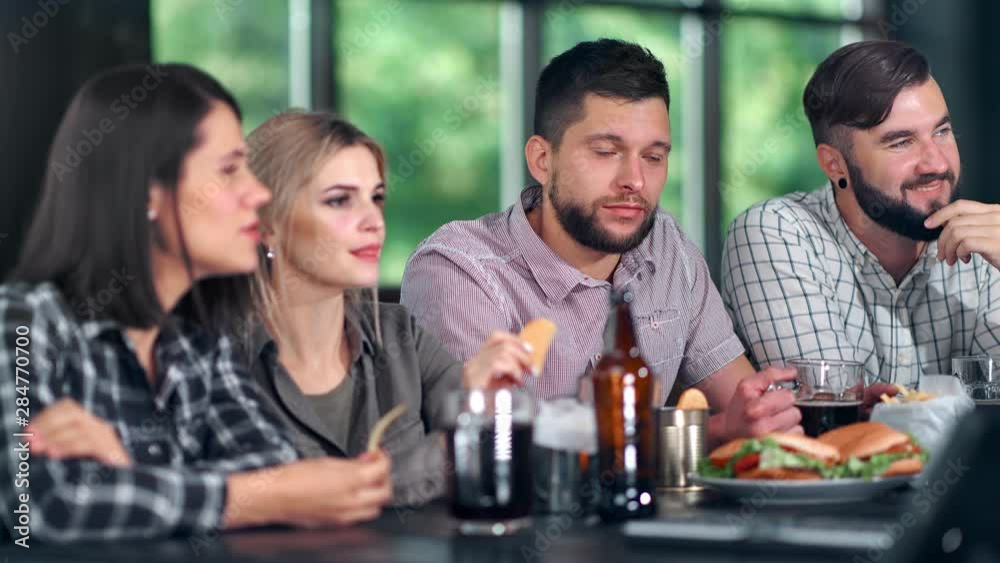 Attractive guy and girl relaxing at pub watching TV discussing sport football championship Attractive guy and girl relaxing at pub watching TV discussing sport football championship