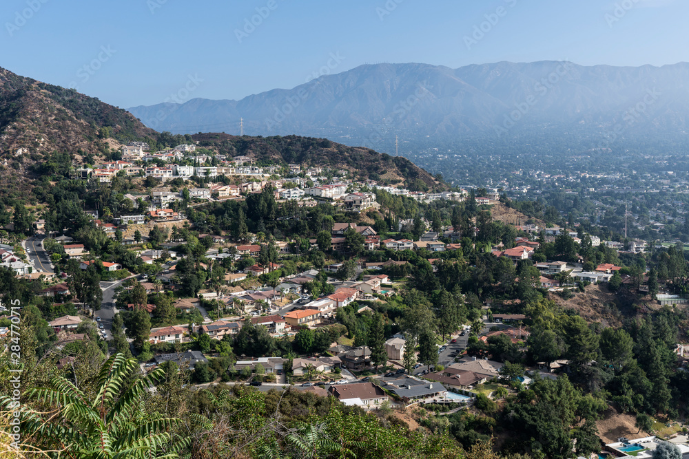 Upscale hillside homes near Los Angeles in Glendale California with morning mist and San Gabriel mountains in background.