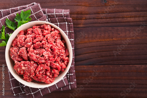 Φωτογραφία Fresh raw ground or minced beef meat in bowl, photographed overhead on dark wood