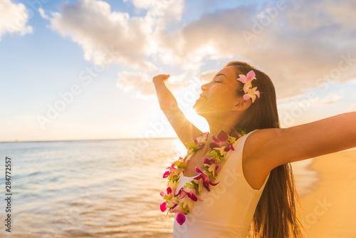 Hawaii hula luau woman wearing hawaiian lei flower necklace on Waikiki beach dancing with open arms free on hawaiian vacation. Asian girl with fresh flowers hair, traditional polynesian dance. photo