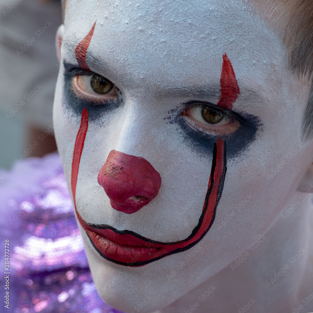 Foto de Halloween Makeup Like Pennywise. Street performer clown with a  white face. The look of a man in the guise of IT on a costume cosplay show.  Close-up. do Stock