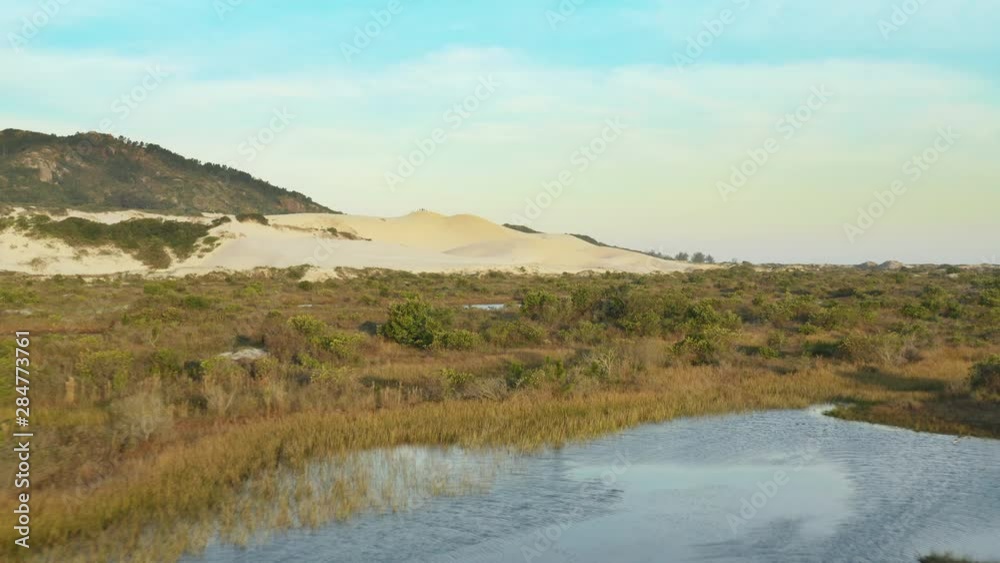 Low aerial cinematic view of sandbanks lagoons and sand dunes at Praia Da Joaquina, Florianopolis city, Santa Catarina, Brazil Low aerial cinematic view of sandbanks lagoons and sand dunes at Praia Da Joaquina, Florianopolis city, Santa Catarina, Brazil