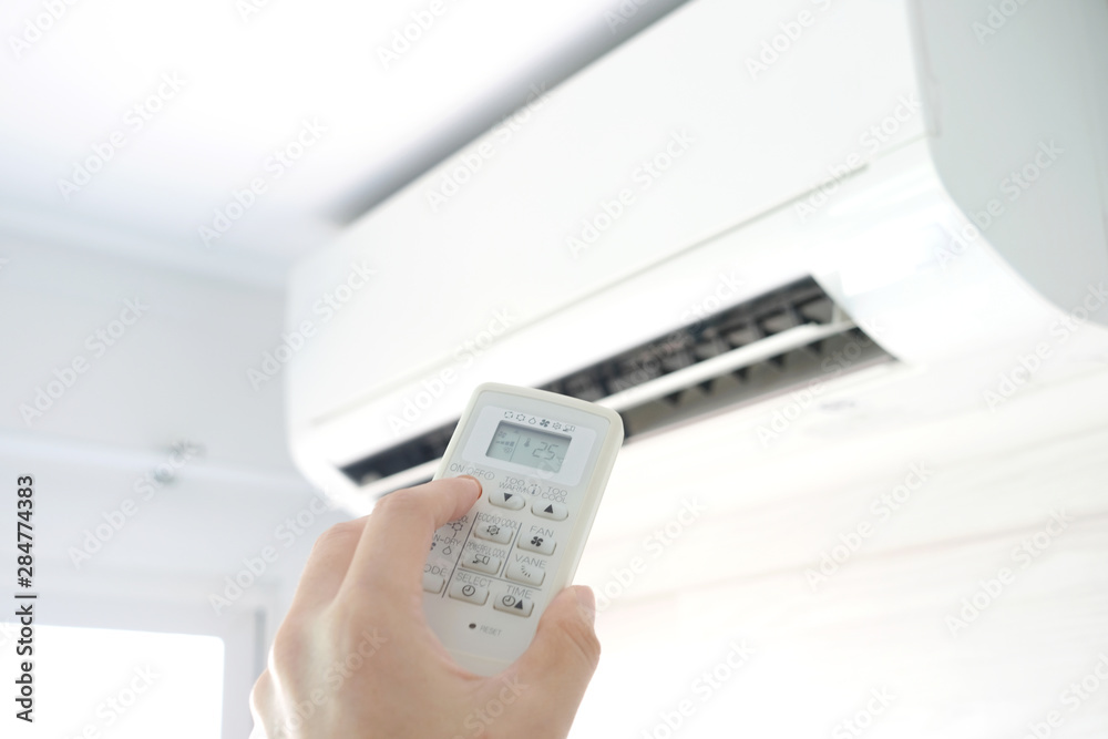 Man's hand using remote control open The air conditioner is cooled to 25 degrees Celsius in his bedroom. Health concepts and energy savings Man's hand using remote control open The air conditioner is cooled to 25 degrees Celsius in his bedroom. Health concepts and energy savings
